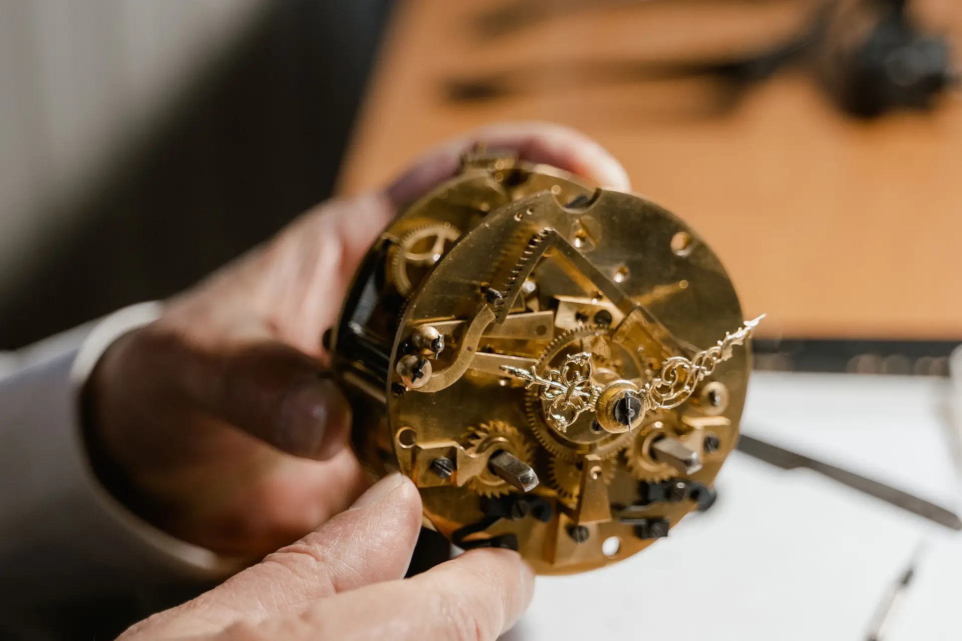 Antique clock movement held in both hands for examination