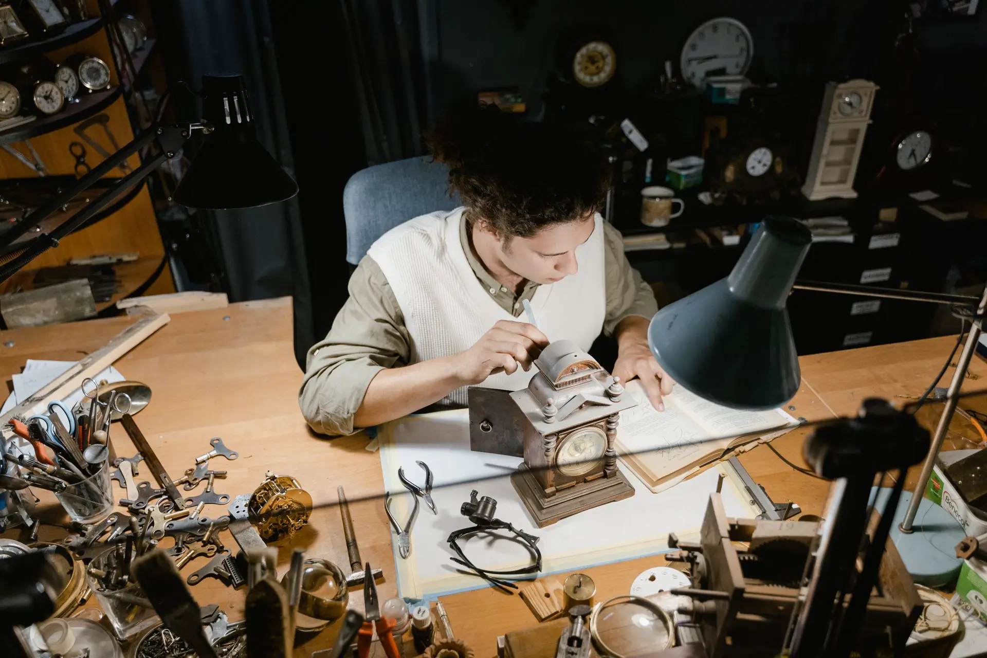 Watchmaker working under a bench lamp on a small movement