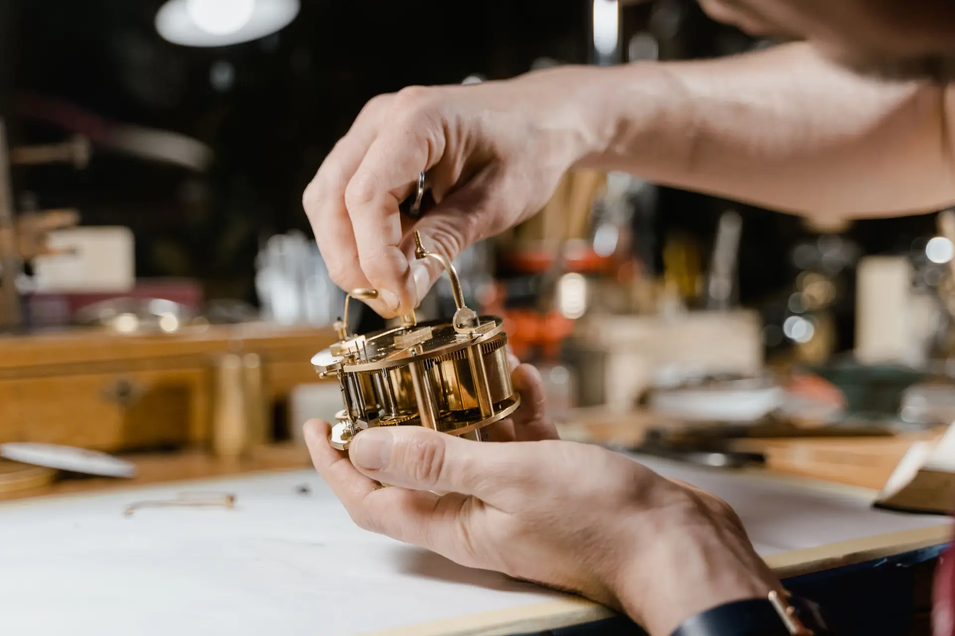 Hands working on a clock mechanism at the bench
